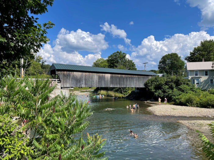 Waitsfield's Great Eddy Covered Bridge over the Mad River. People swim and play underneath.