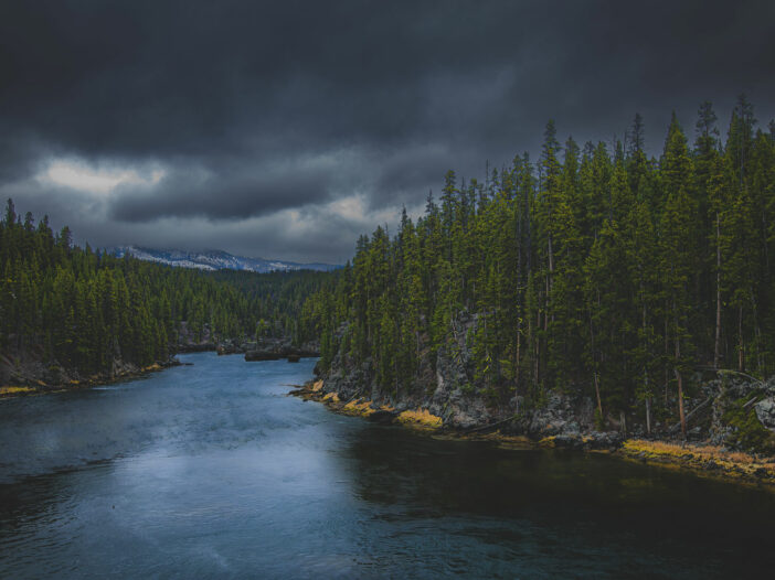 Yellowstone River with dramatic clouds. Green trees line the banks.